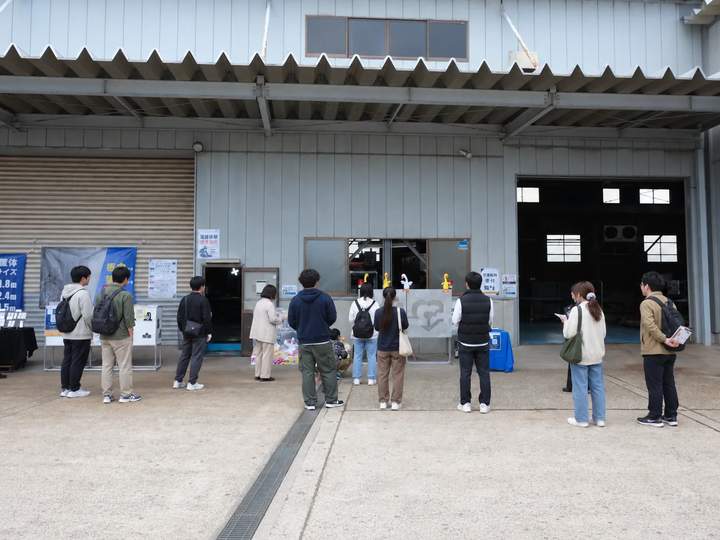 金属加工工場の敷地で開催された地域・家族向けイベントで、体験型集客装置に集まる来場者